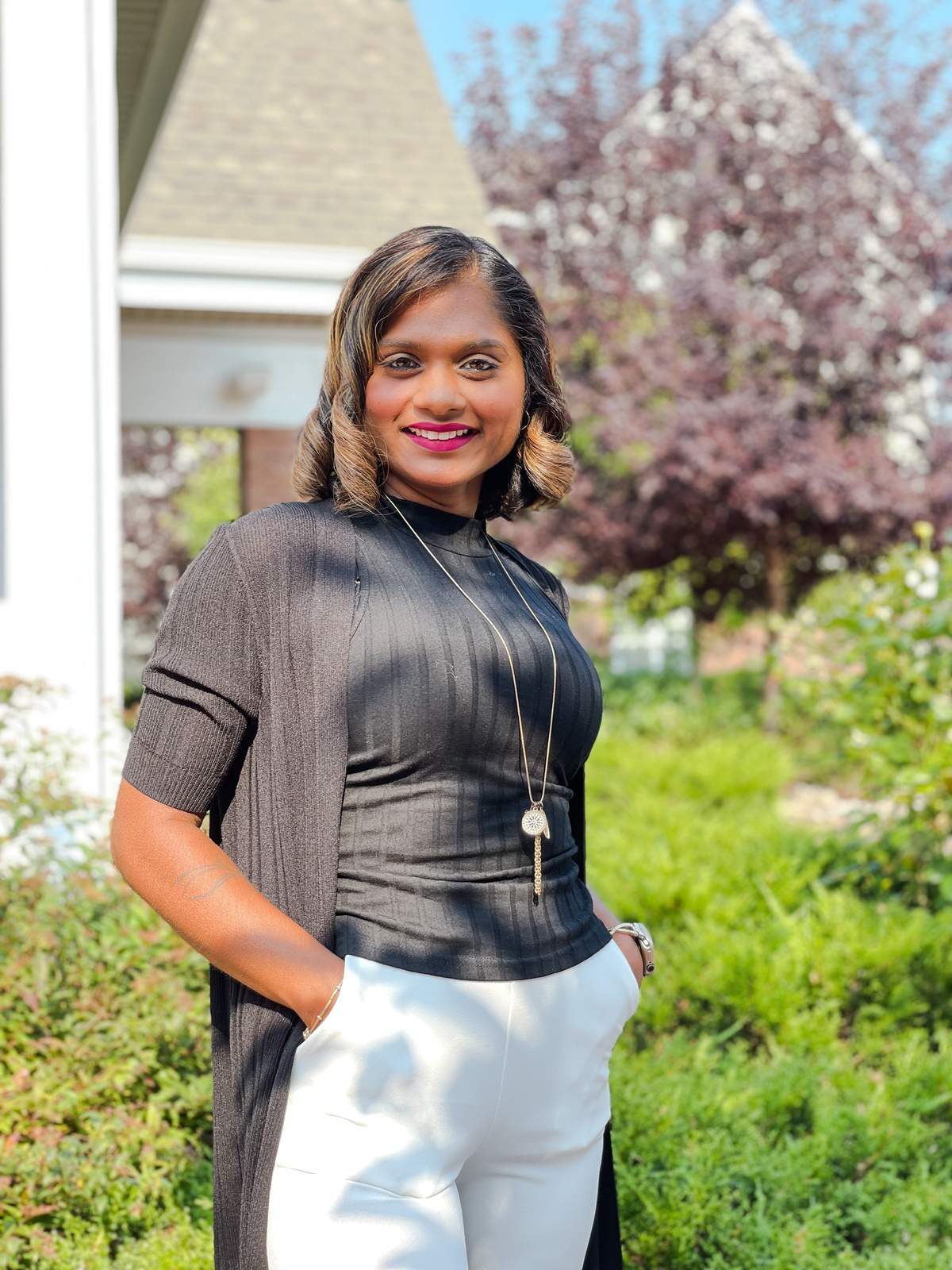 Mina Gagraj standing outside, smiling, with trees and a house behind her.